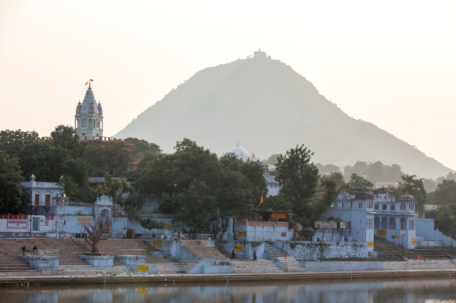 Serene riverside temples at the foot of a lush hill at dusk