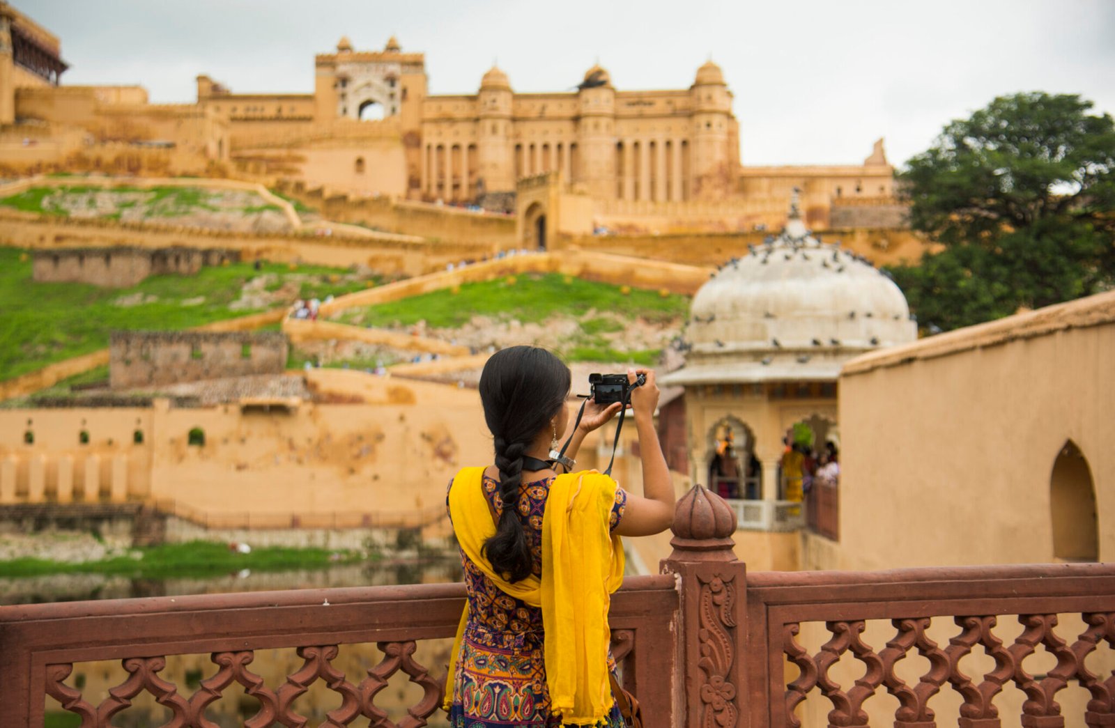 Woman tourist taking a photo of the Amer fort, located in Jaipur, India.