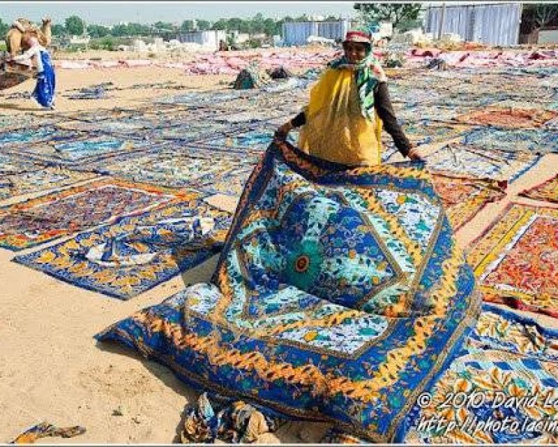 An old woman is lying down clothes that will dry on direct sun.